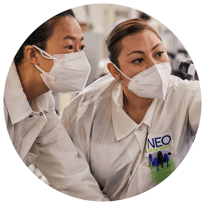 Two NeoGenomics lab employees looking at images on a screen